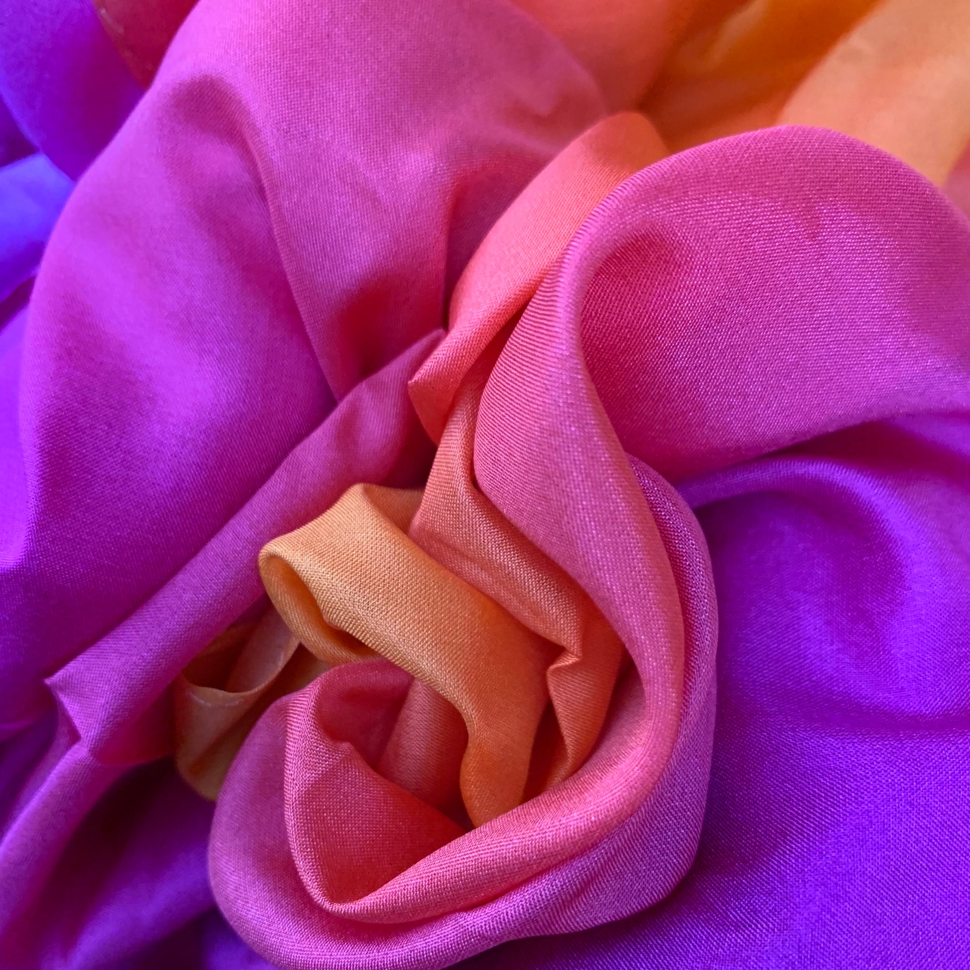 Close-up of autumnal pinks and oranges silk fabric in folds with a soft focus