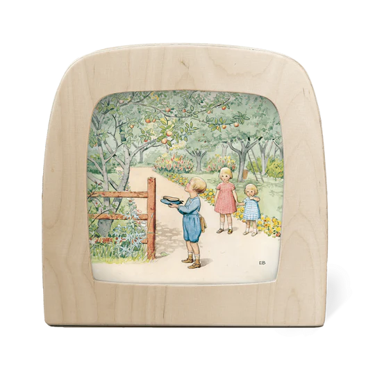 A wooden silhouette screen featuring an illustration of a boy catching apples from a tree in his hat watched on by two girls