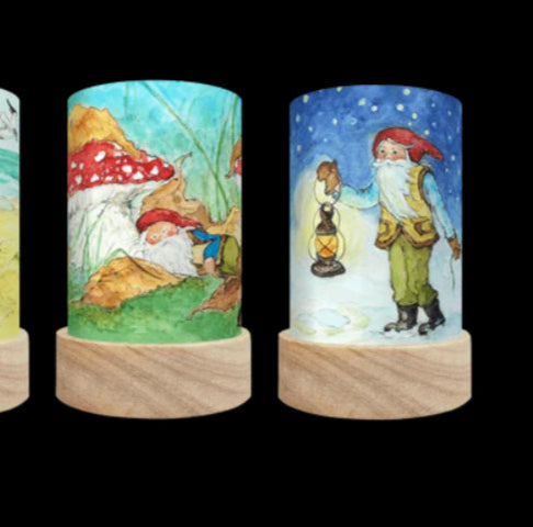 two scenes showing George the Gnome with a red hat: sleeping under a red toadstool, and walking with a lantern through the snow