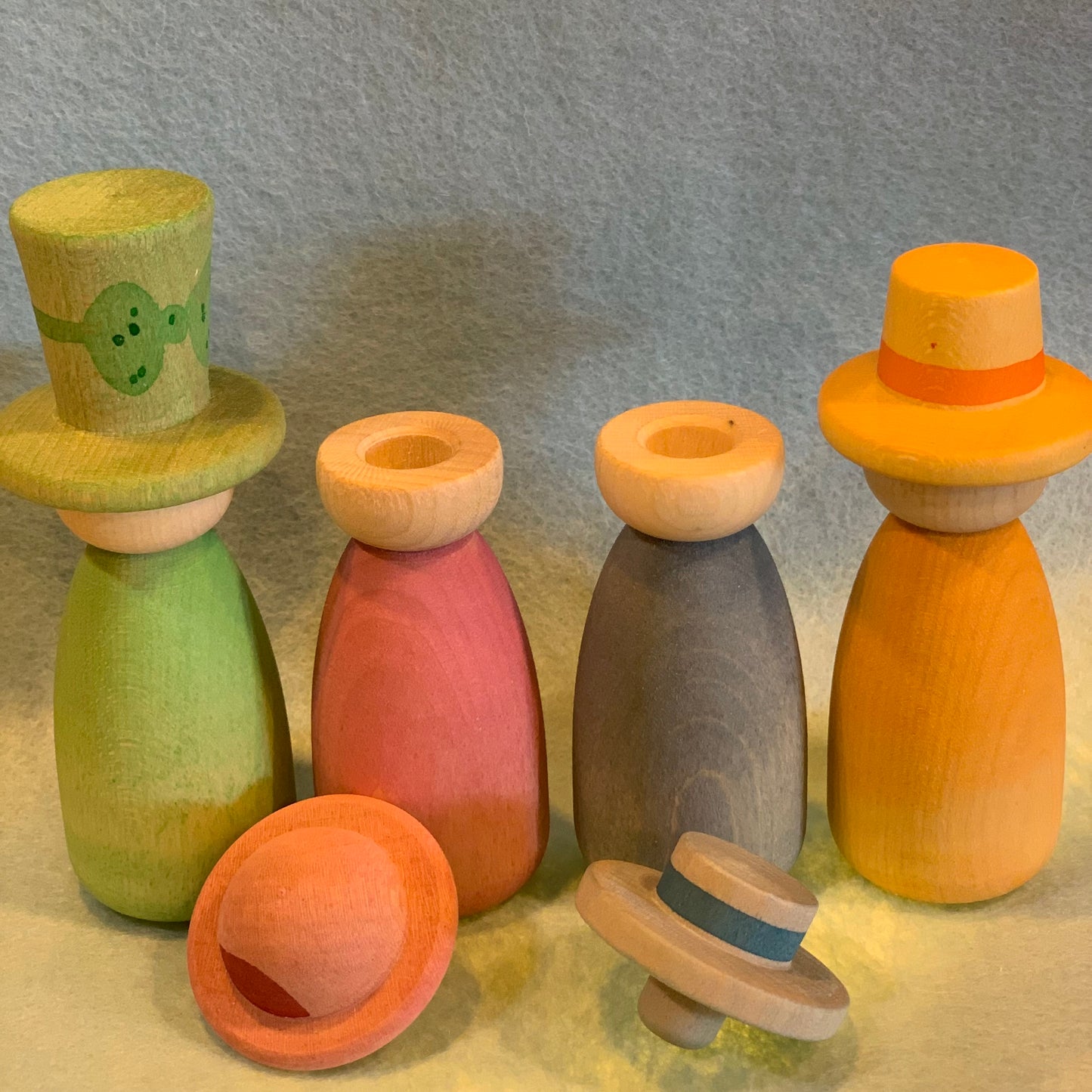 Four of the colourful wooden peg dolls from a set of twelve, with mix and match hats