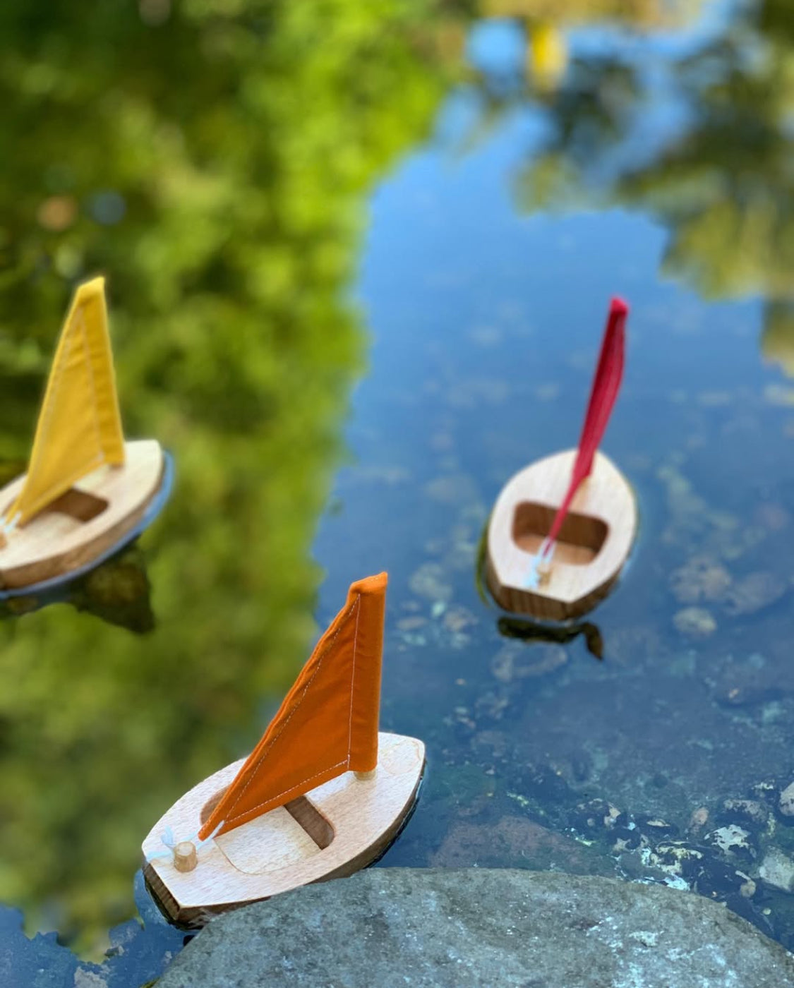 Toy wooden sailboats testing the water