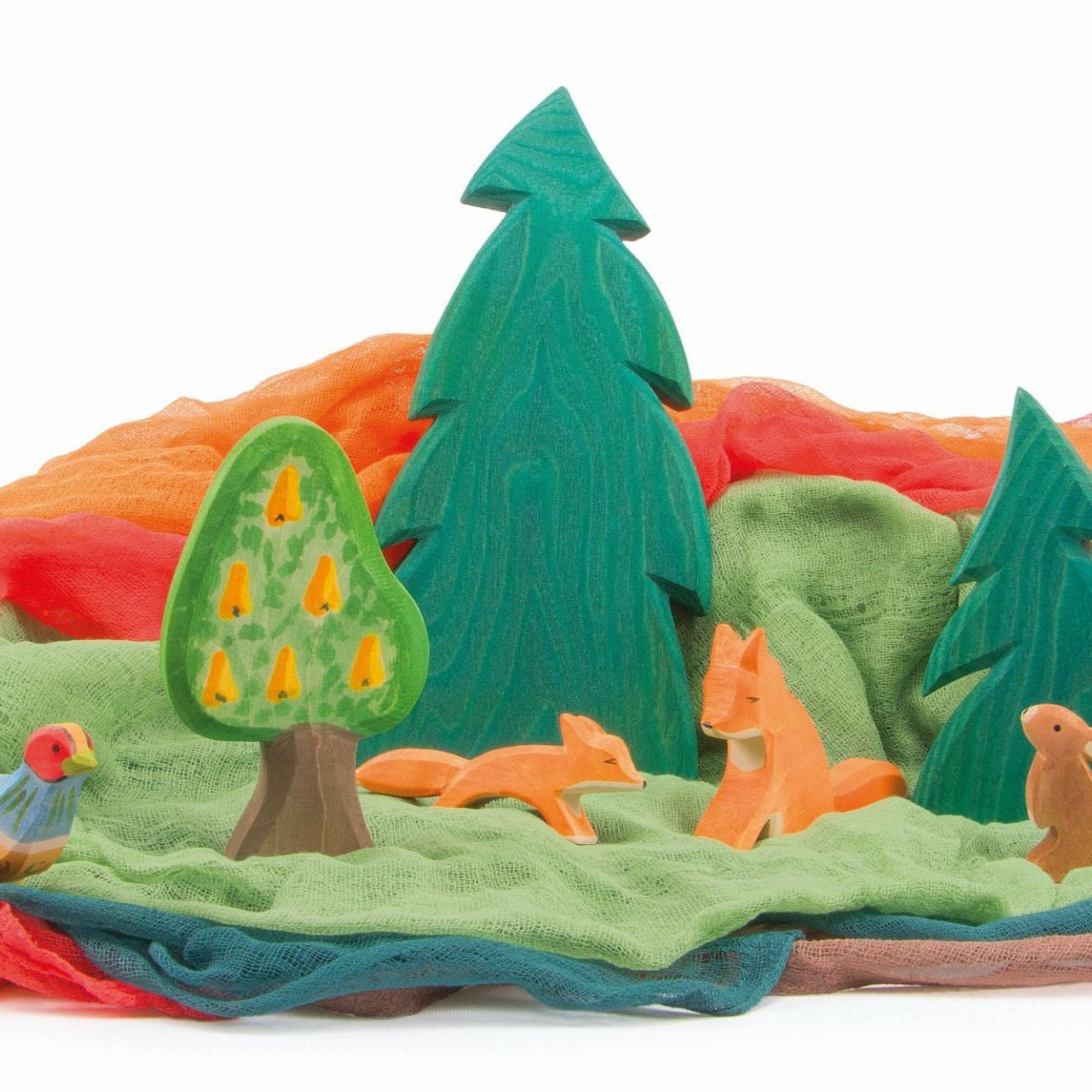 Wooden toy Autumn landscape with trees, animals, and colorful muslin fabric ground cover drapes on a white background