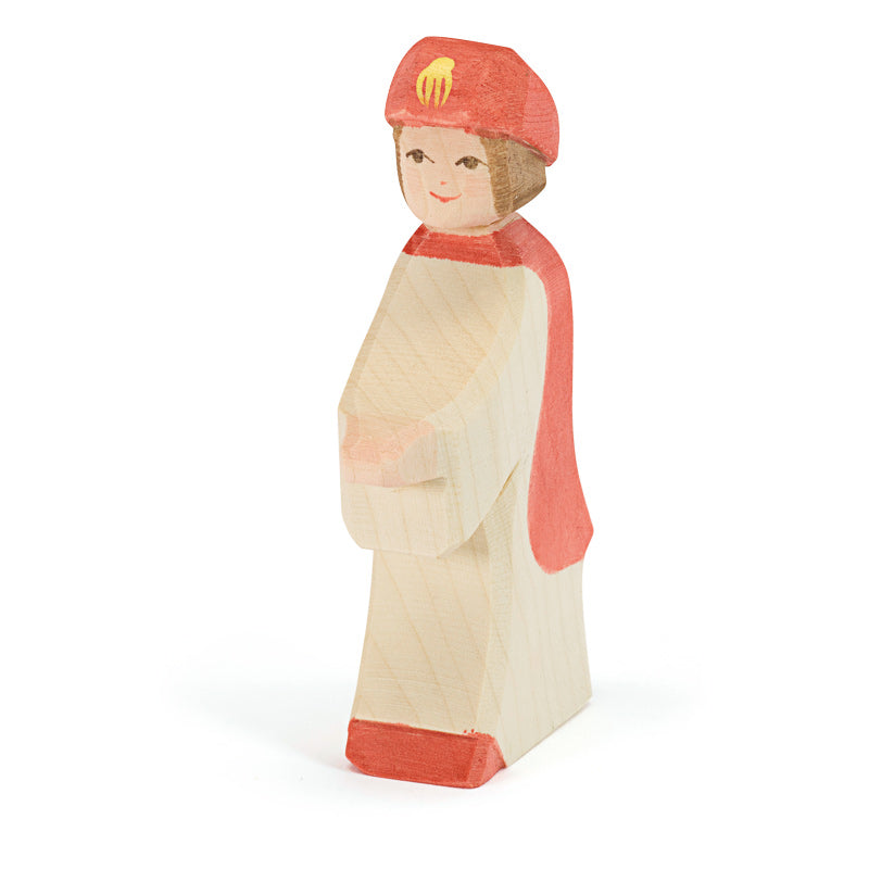 Wooden figurine of a page boy wearing a red cap and cape with a white gown on a white background