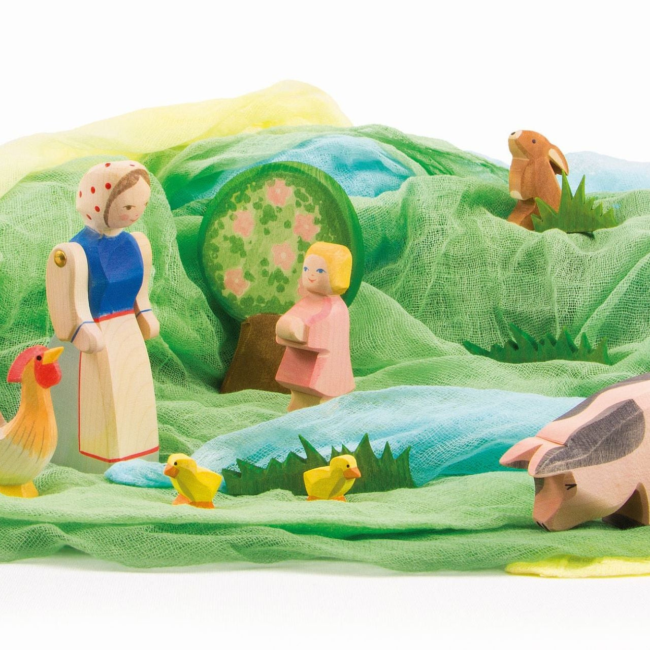 Wooden toy farm set with figures and animals on a Spring green landscape