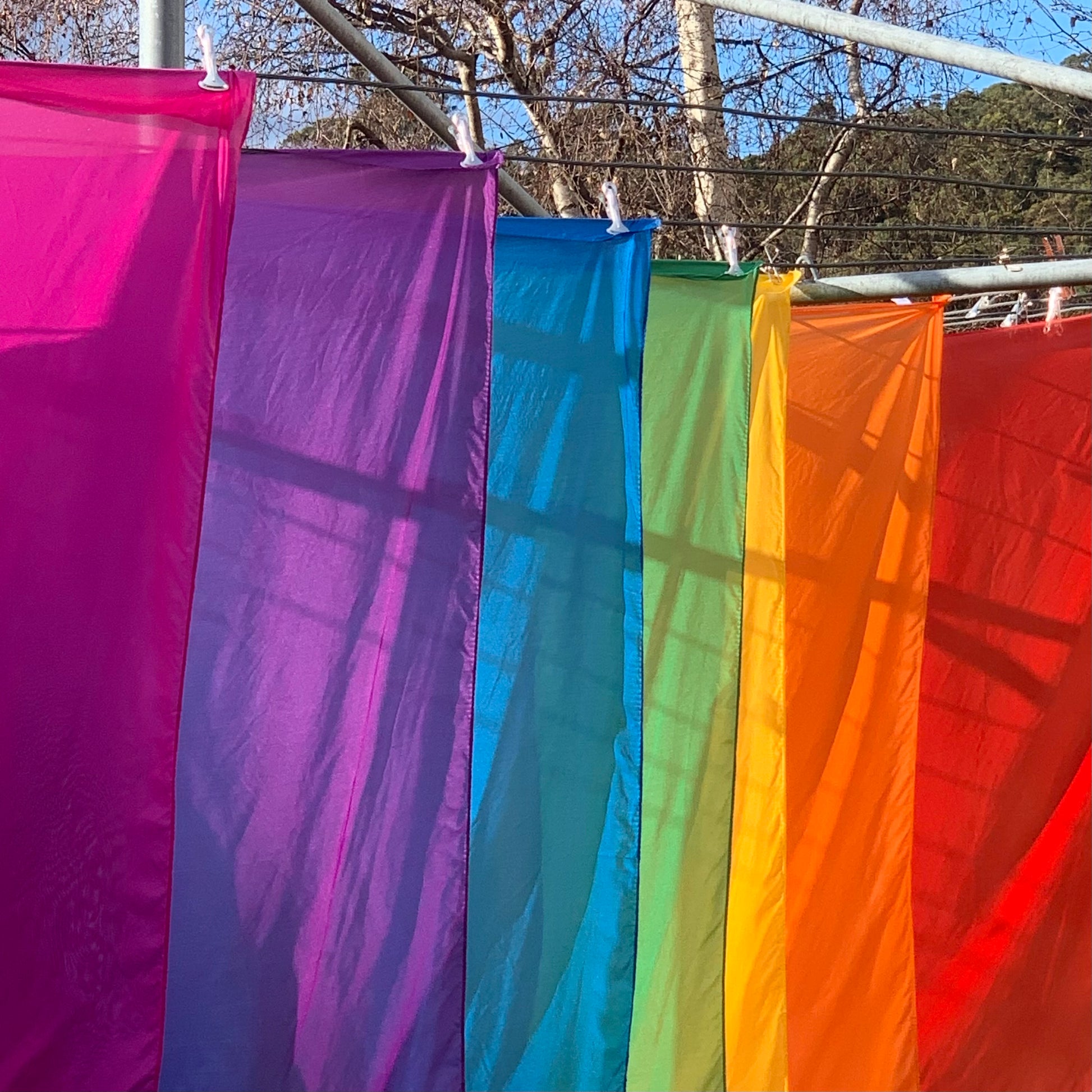 Seven shades of the rainbow in silks hung to dry on a hills hoist clothesline