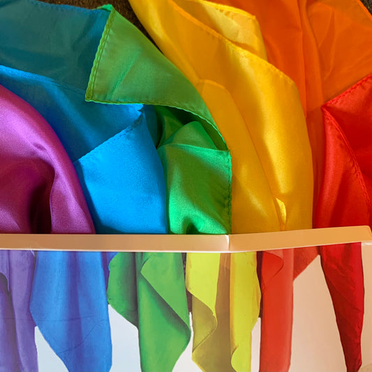 Colorful mini size play silks arranged in a rainbow order to match the packaging photo below