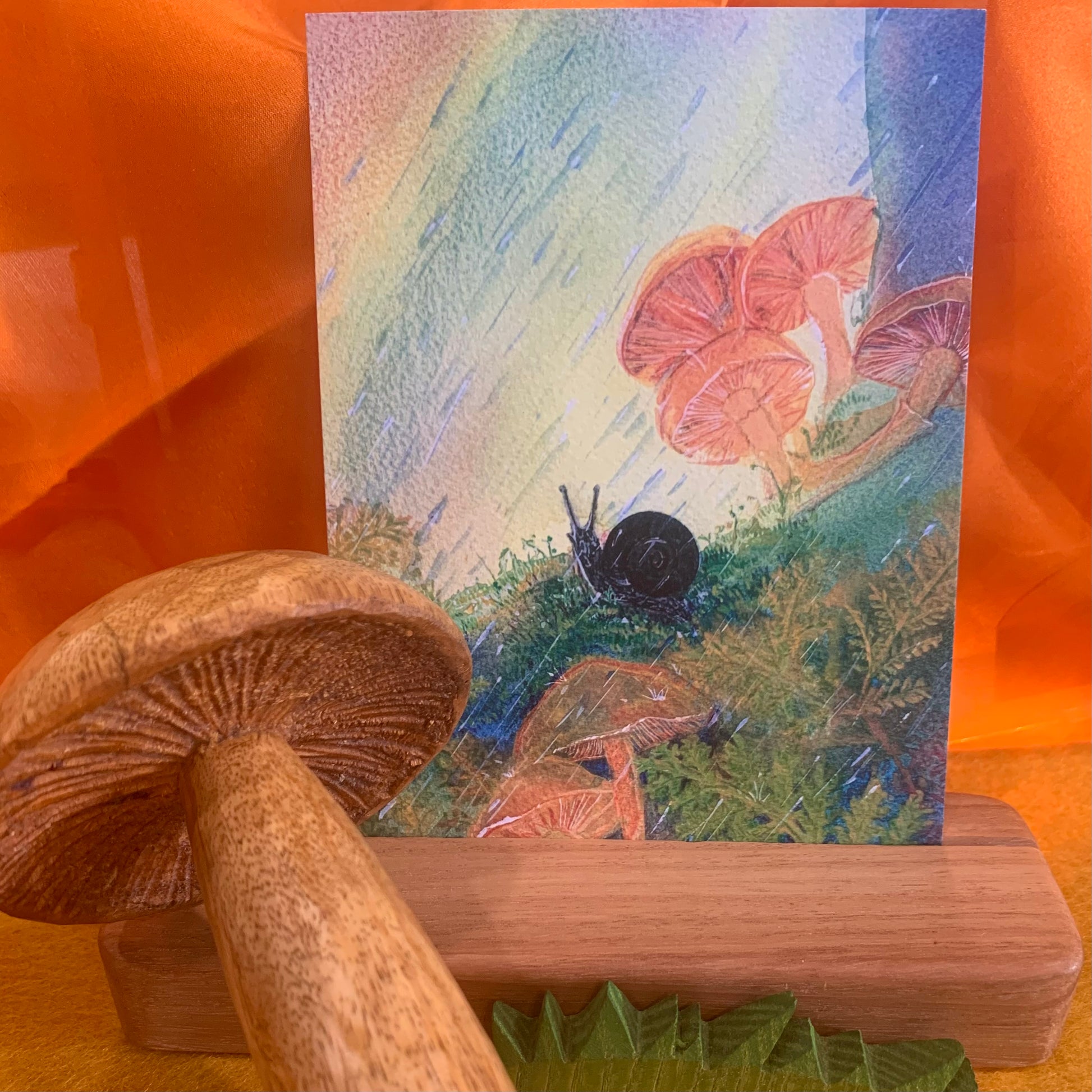 Art card of an Otway Snail, (pictured with items sold separately: a handmade wooden car holder, Ostheimer grass, and a hand crafted wooden darning mushroom