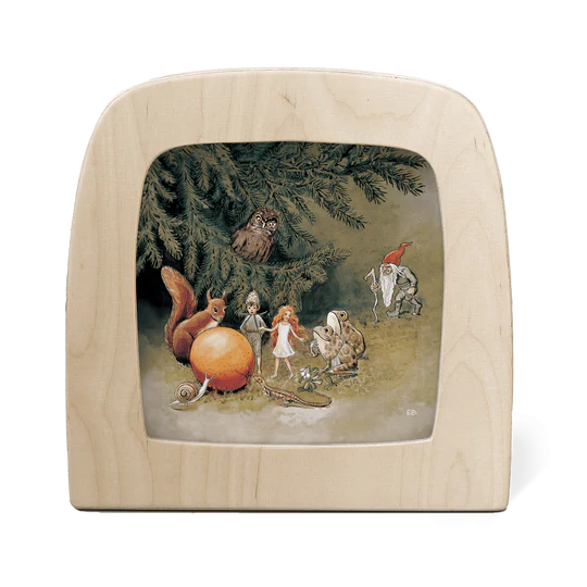 A wooden silhouette screen featuring an illustration of a an owl sitting on a tree branch observing fairy folk and animals trying to guess what a large orange ball coul be