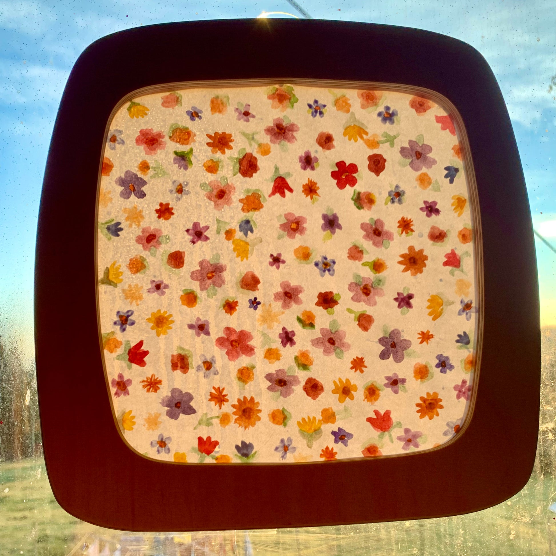 Toverlux DIY paper with painted flowers, displayed in the Toverlux window frame at sunrise