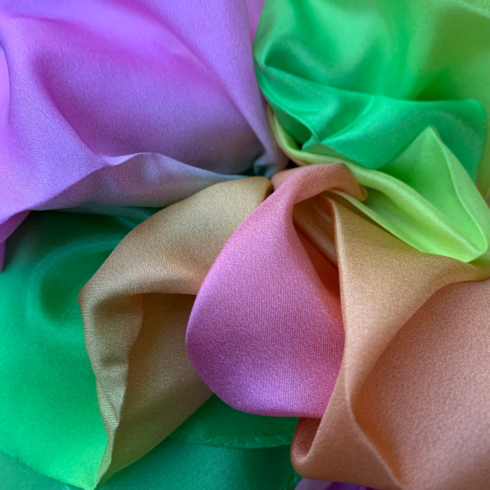 Close-up of gathered up colorful silk fabric in pink, green, and gold.
