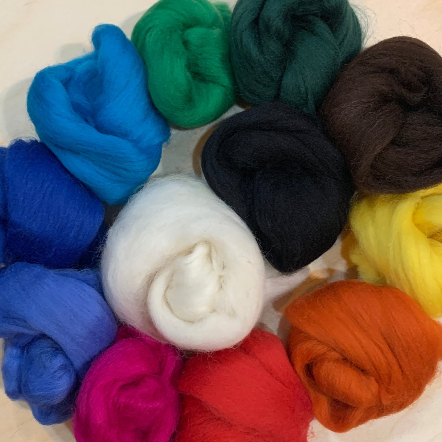 Assorted colourful wool fleece bundles on a wooden board