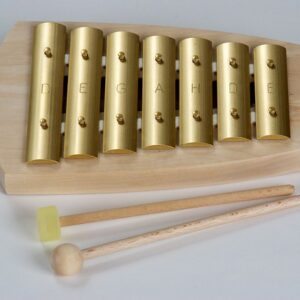 A glockenspiel with brass keys with a wooden and a rubbler tipped mallet on a light background