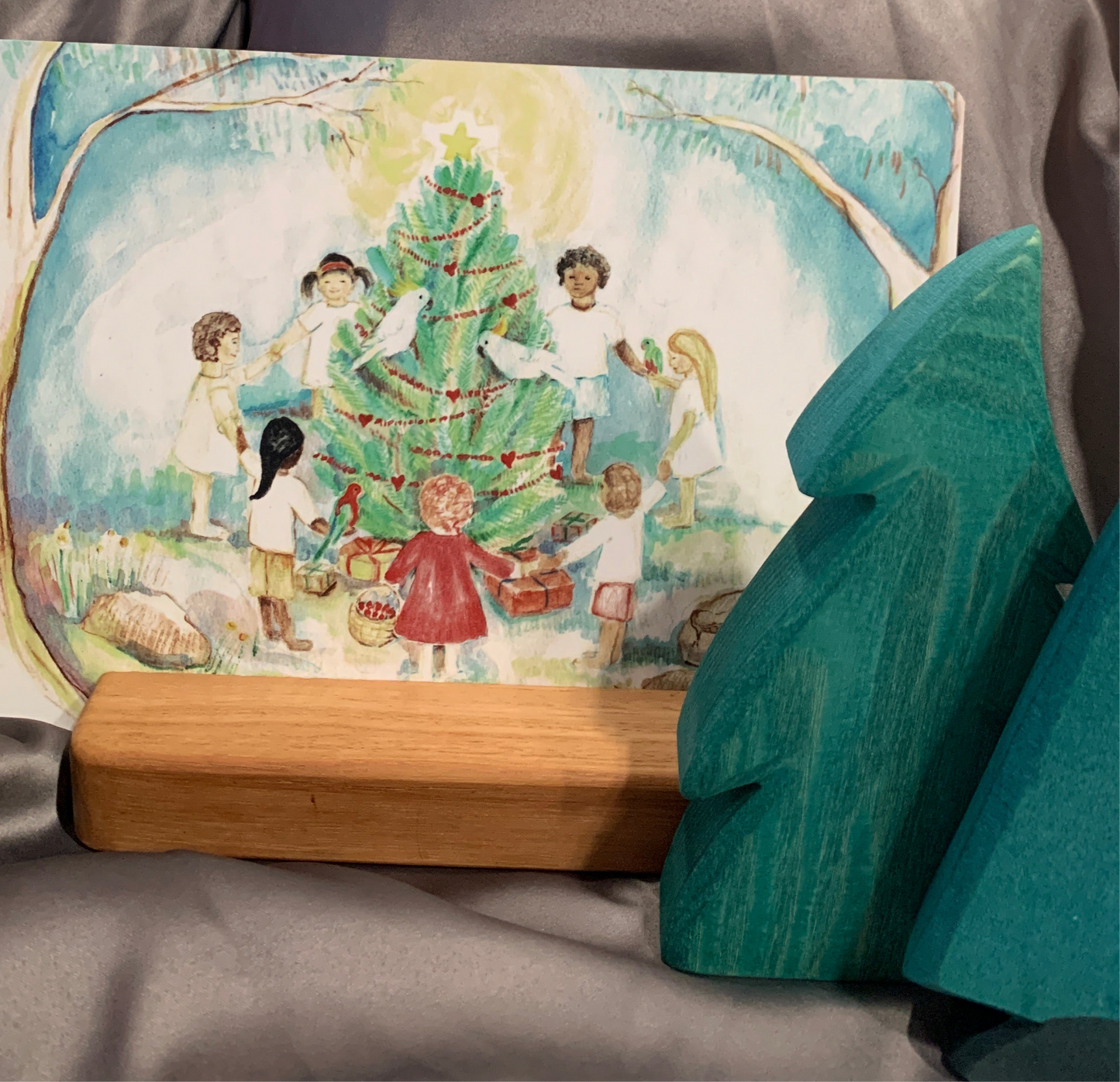 Postcard depicting Xmas on a display stand with wooden trees 