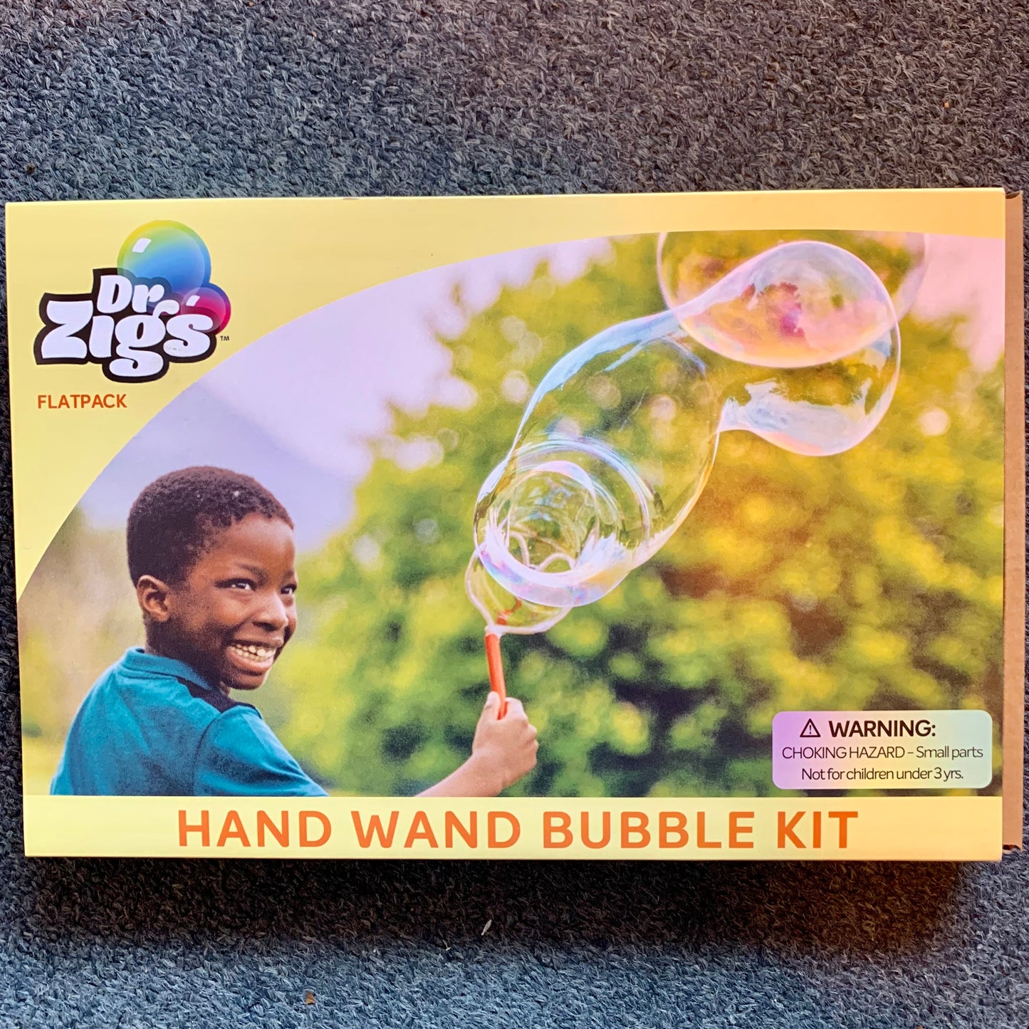 Dr. Zigs hand wand bubble kit packaging with a child blowing bubbles on a grey background