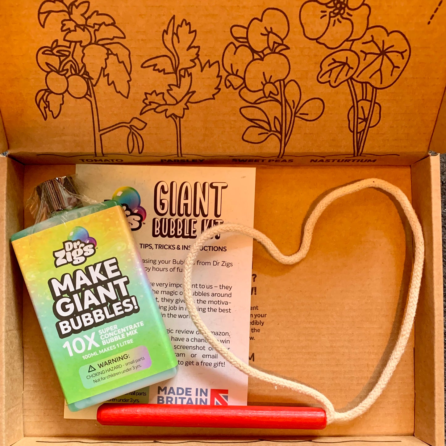 Dr. Zigs bubble solution,hand wand, and instructions in a cardboard box with floral designs.