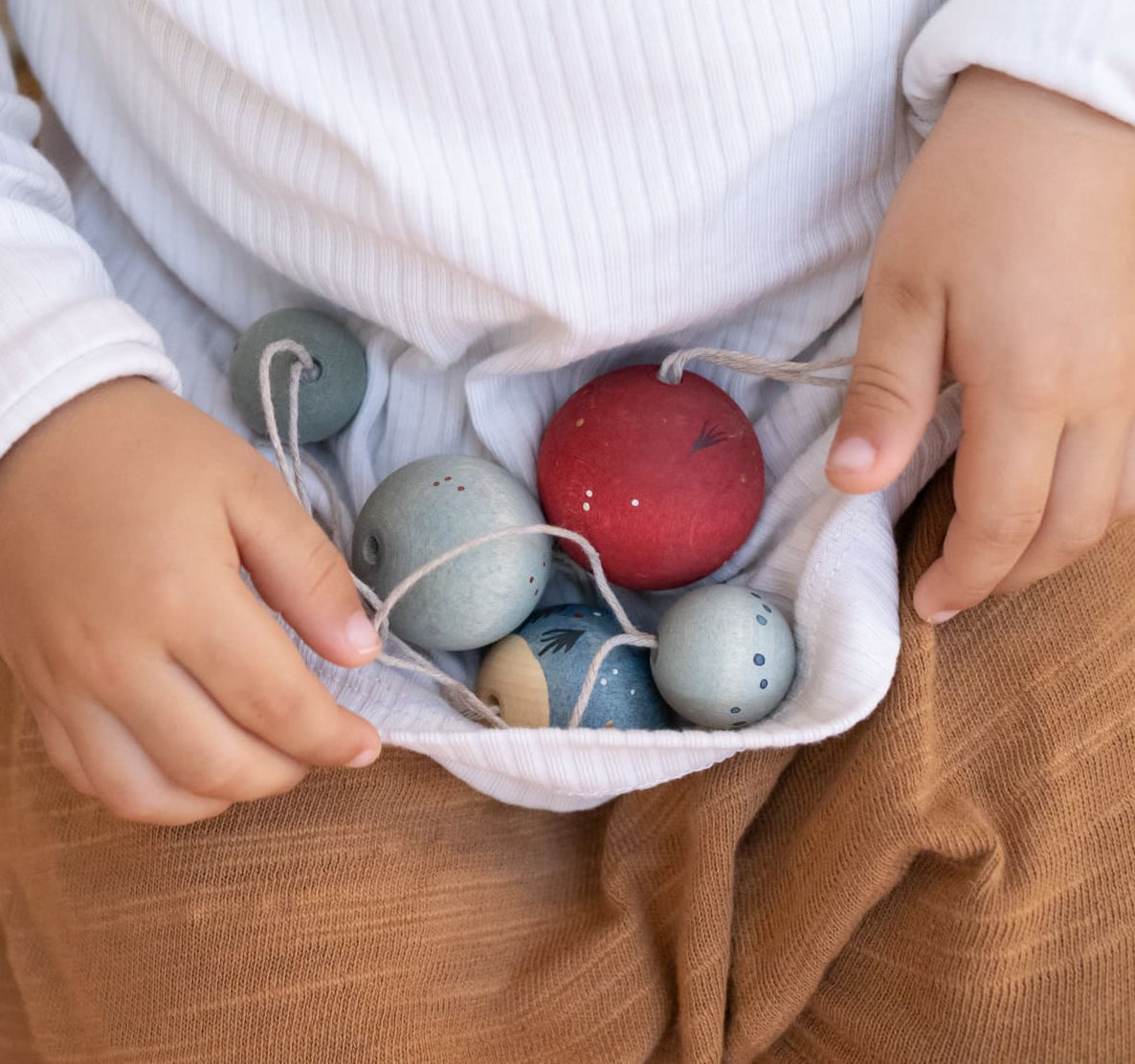 Child holding colourful wooden Christmas baubles in their lap