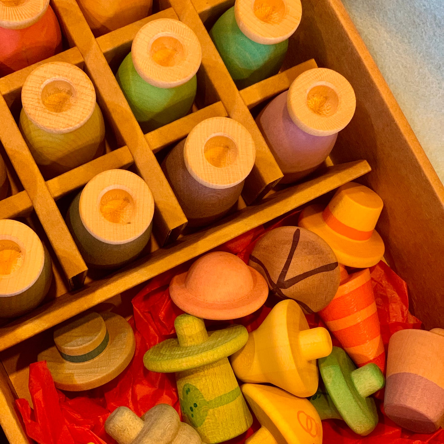 Wooden toy figures and their hats inside a box with a focus on mix and match hats