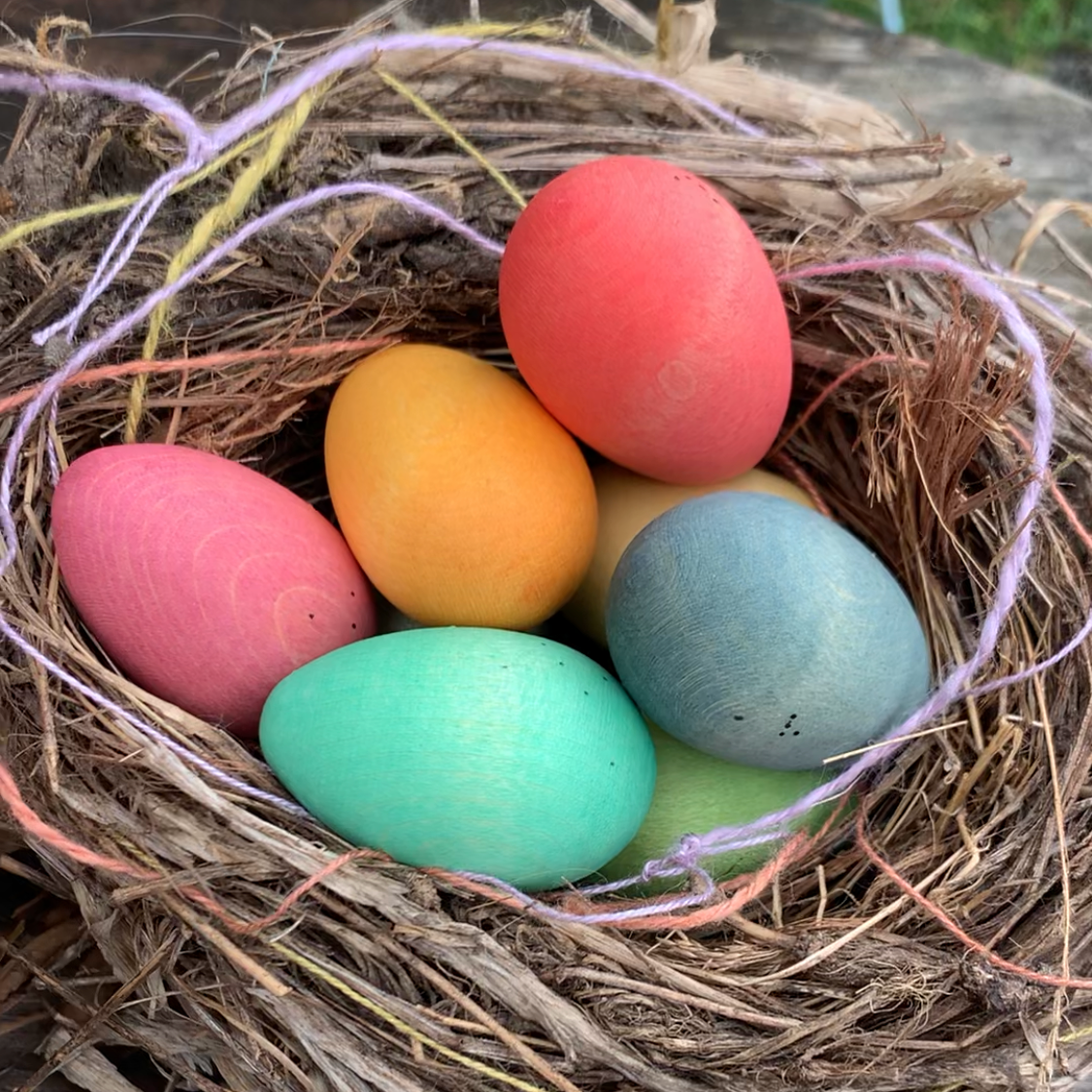 Hand painted wooden eggs in pastel colours in a birds nest 