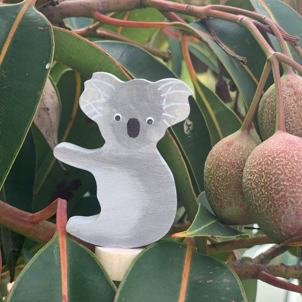 wooden handpainted koala figurine on a eucalypt branch 