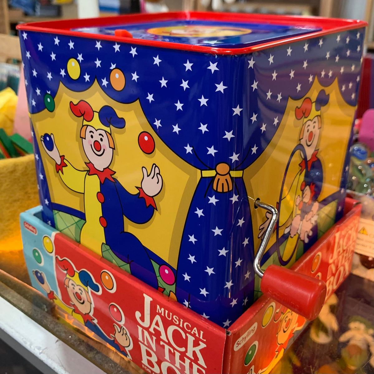 A traditional Jack in the Box toy with a colorful illustrated tin box featuring a clown and stars.