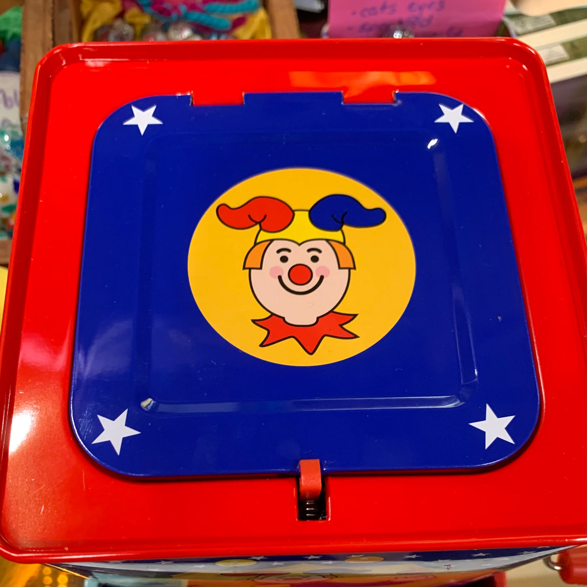 Red lid of  toy Jack in the box with a clown face on a blue background
