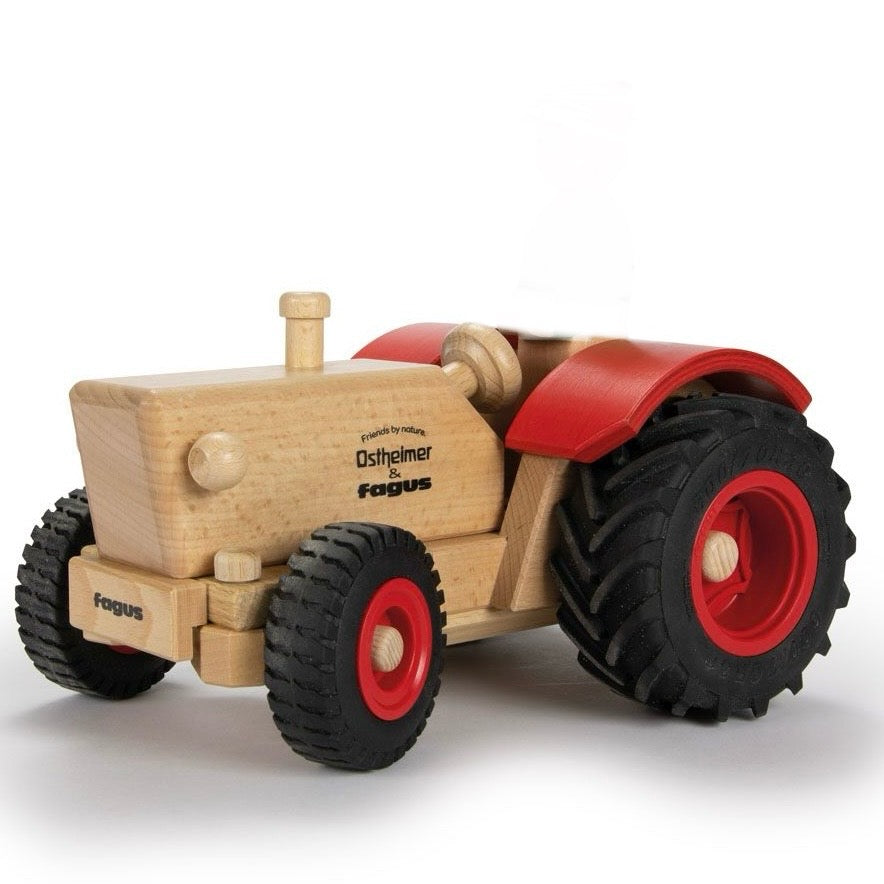 A wooden toy tractor by Fagus, featuring a natural light wood body, red fenders and wheel centers, and black rubber tires, photographed on a clean white background.