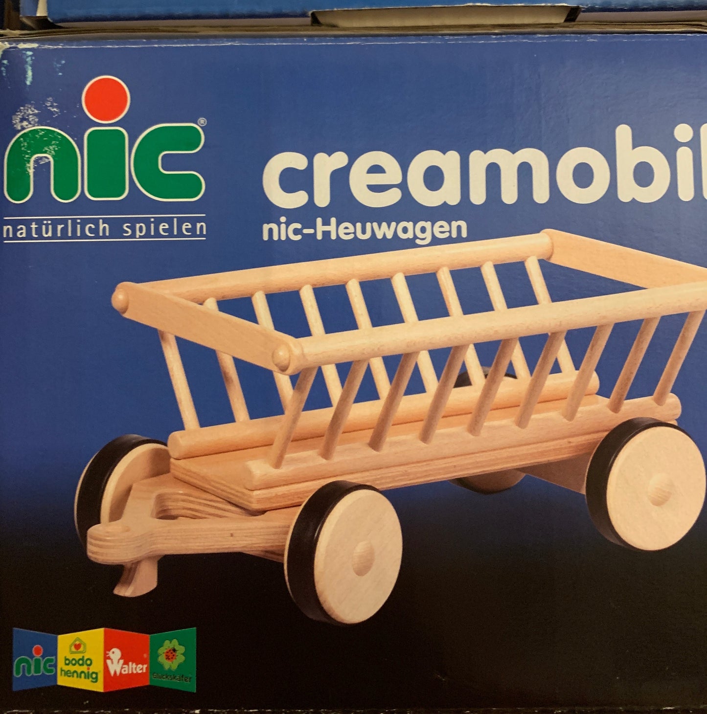 Wooden toy hay wagon on a blue box featuring the brand 'nic'.