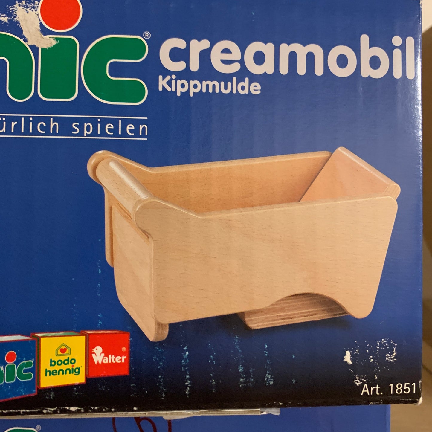 Box of a wooden toy skip truck with 'creamobil' branding on a blue background