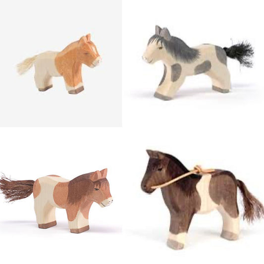 A set of four wooden toy ponies, three Shetlands and one pony with reins, painted in various colors and equipped with sisal rope tails.