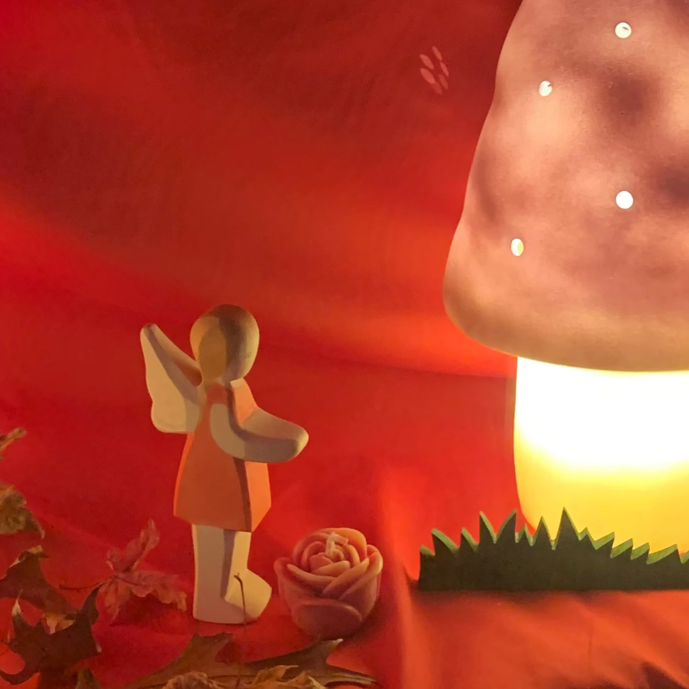 Decorative mushroom lamp with fairy figure and fairy lights on a red fabric background