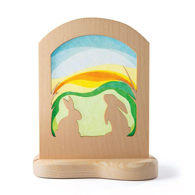 Wooden  frame with a silhouette scene of rabbits against a colorful sky.