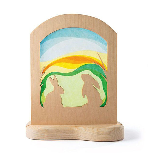 Wooden  frame with a silhouette scene of rabbits against a colorful sky.