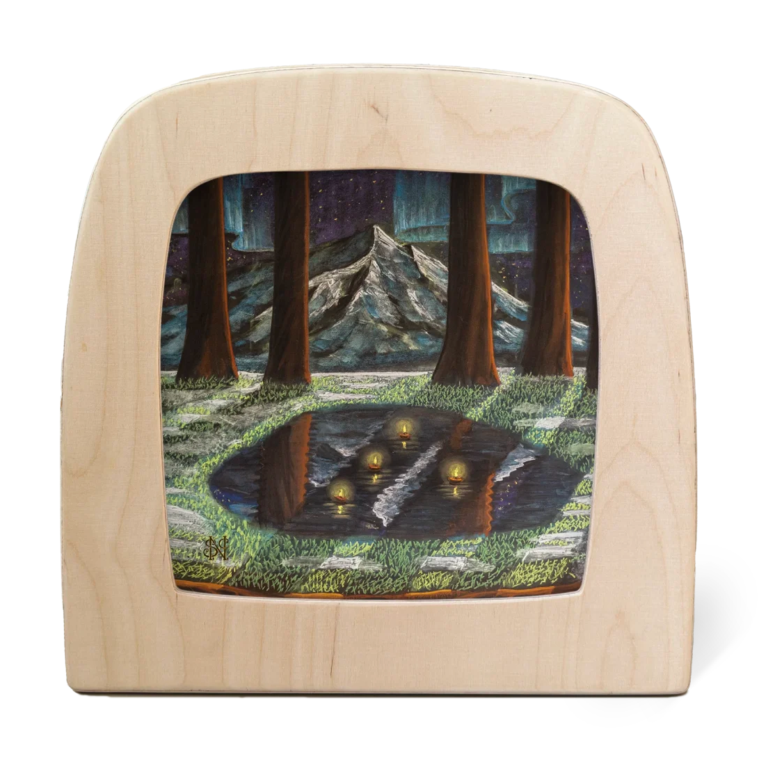 Wooden frame with a chalkboard artists landscape wintery scene of trees and mountains in a clearing with winter lights floating on a forest lake.