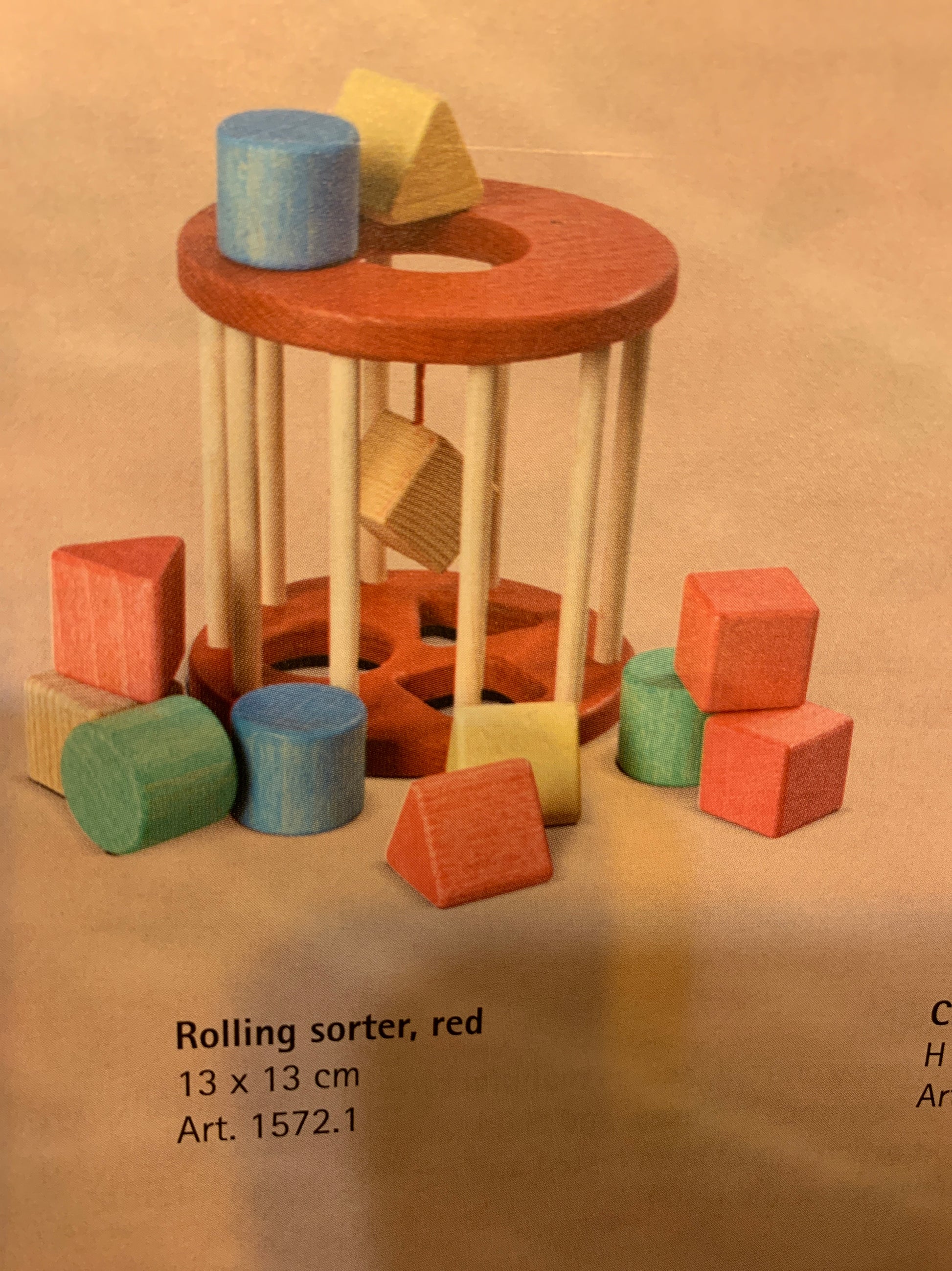 Wooden rolling sorter toy with colorful blocks on a beige background