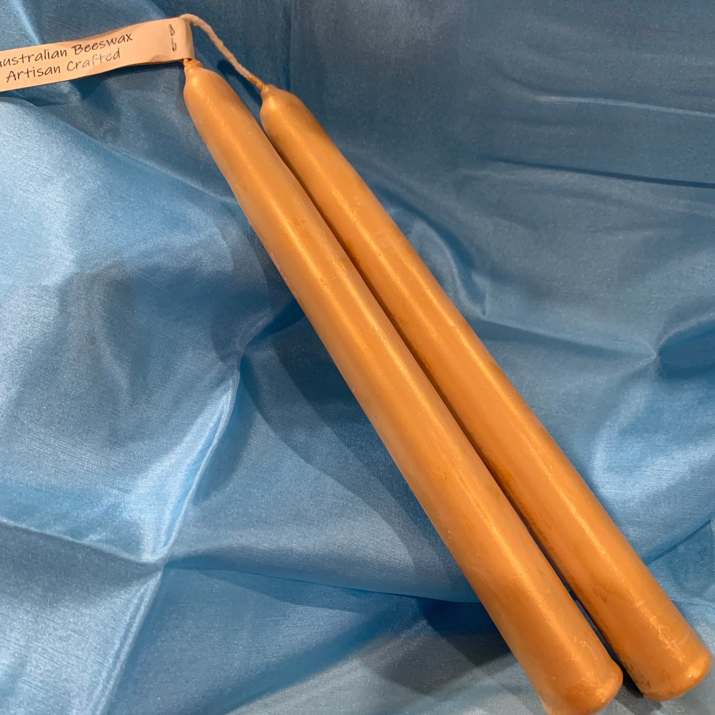 golden beeswax candles on a blue silk background