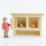 Small wooden hutch with an ostheimer farmer figure of a and a toy rabbit and hen on a white background