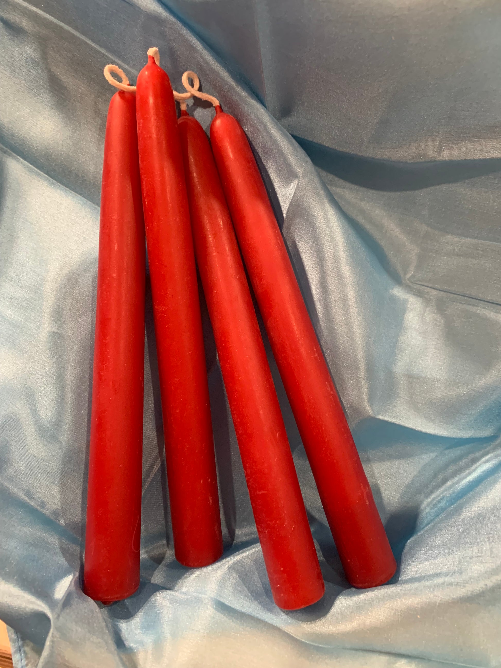 red handmade beeswax candles in a grey silk backdrop