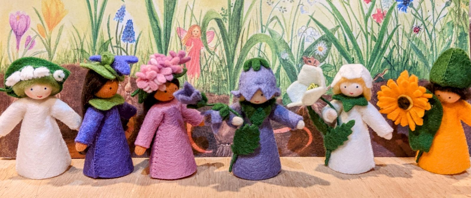 Row of pretty felt fairys with a hand drawn crayon floral background 
